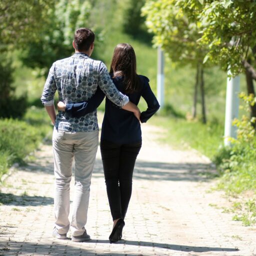A couple walking down a sunny path with trees